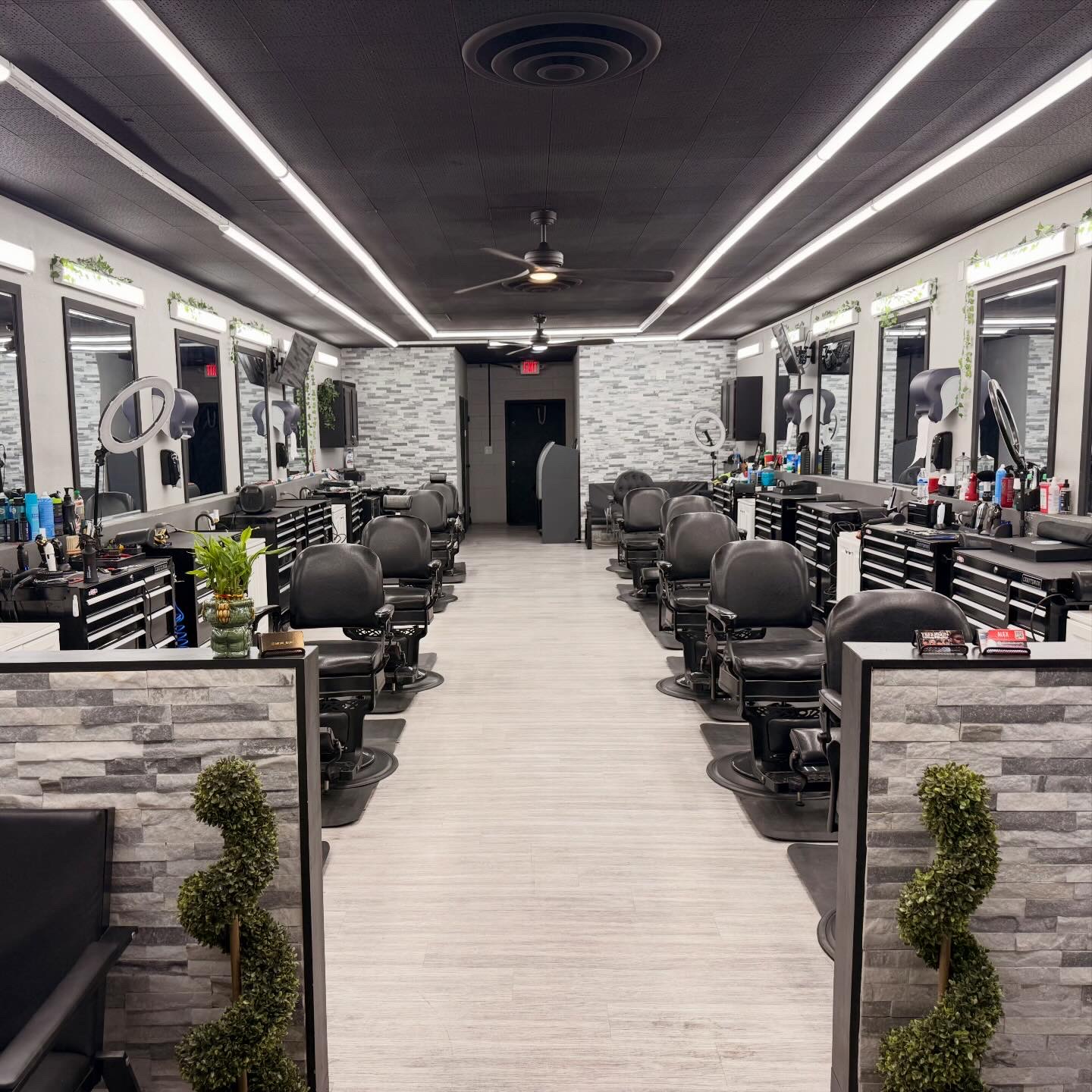 Clean modern barbershop interior with rows of black barber chairs and stone accent walls